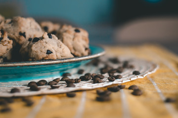 dark chocolate cookies and scattered coffee beans on a yellow plate on yellow background