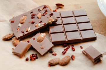 A bar of milk chocolate. Homemade milk chocolate with almonds and dried strawberries. Pieces of milk chocolate. Unlabeled milk chocolate bar