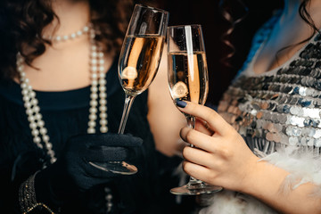 close up glasses of champagne. flappers women wearing in style of roaring gatsby twenties drinking a