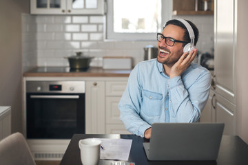 Wall Mural - Man listening music on headset while using laptop.