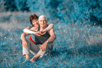 Mature beautiful couple in love on a green lawn in a park on a summer sunny day.