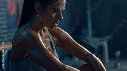 Beautiful Strong Fit Brunette in Sport Top and Shorts in a Loft Industrial Gym with Motivational Posters. She\'s Catching Her Breath after Intense Fitness Training Workout. Sweat All Over Her Face.