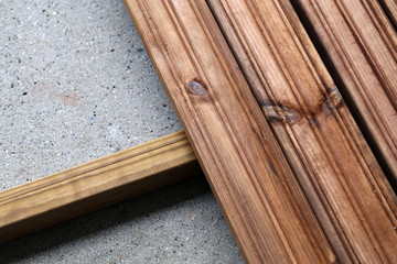 DIY building a porch / balcony floor with brown wooden planks in Espoo, Finland, spring, 2020. In this photo you can see the floor in progress and cement under it. Closeup color photo.