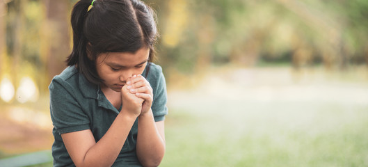 Pray concept.Asian child praying,hope for peace and free from disease,Hand in hand together by kid ,believes and faith in christian religion at church-panoramic banner for web header