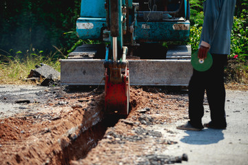 Backhoe is digging road to lay water pipe.