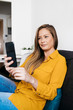 © 2Design - Beautiful adult female sitting on sofa while using smartphone