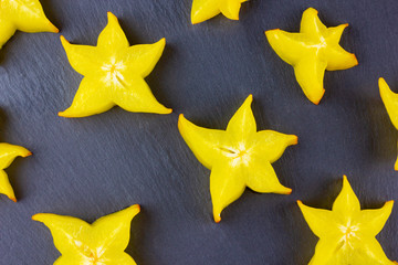 Wall Mural - Carambola on a dark background. Sliced carambola on a black background. Slices of star fruit. Trendy food