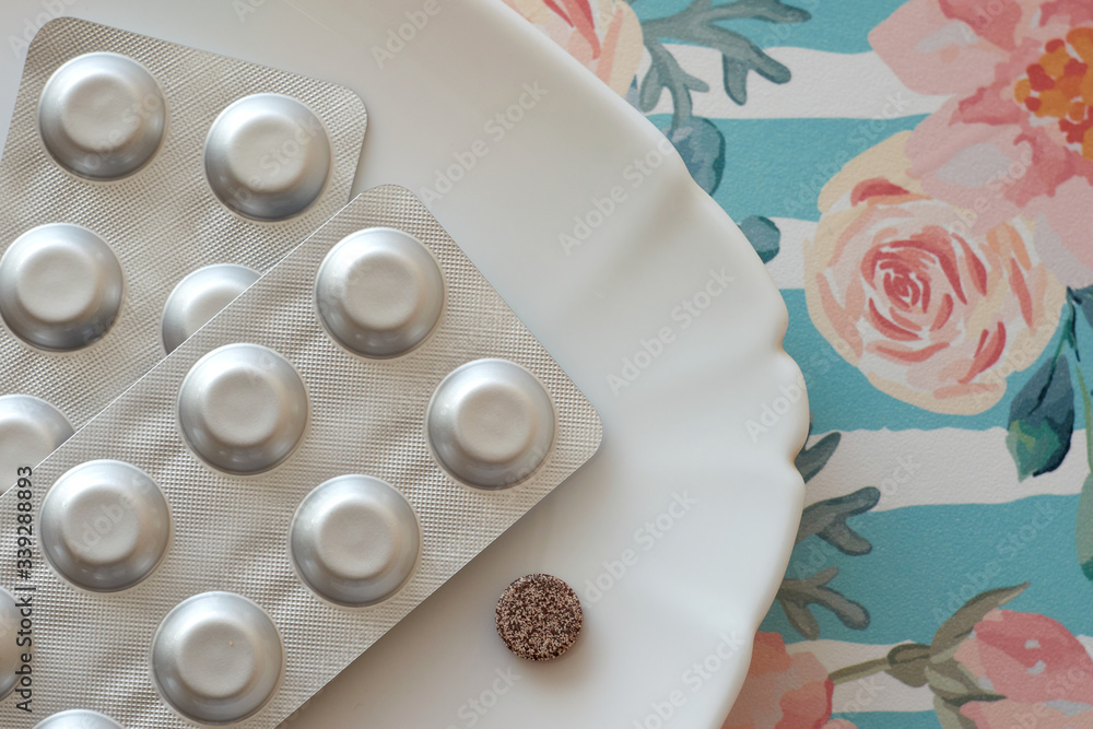 Iron pills on a plate. Many tablets of Ferrous sulfate. Supplement use ...