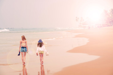 Two girls are walking along the ocean shore.