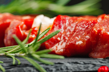 Wall Mural - Raw beef kebab with herbs on a dark board, close up