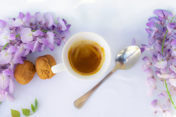 white cup of coffee with strawberries and purple flowers on a table ready for breakfast