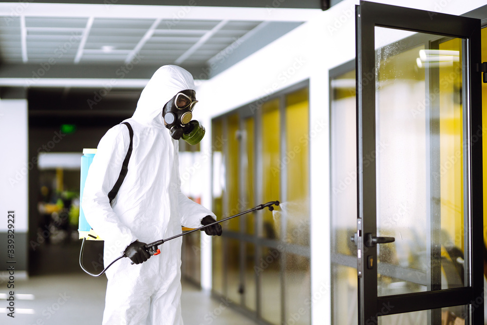 Disinfecting of office to prevent COVID-19, Man in protective hazmat suit with  with spray chemicals to preventing the spread of coronavirus, pandemic in quarantine city. Cleaning concept. - obrazy, fototapety, plakaty 