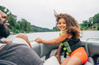 © Inti St. Clair - Smiling happy girls on boat on lake surrounded by trees, wind blowing hair