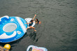 © Inti St. Clair - Overhead shot of girl in life jacket jumping into lake water from giant floaty