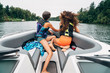 © Inti St. Clair - Girls in life jackets sitting on bow of boat on lake surrounded by trees