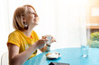 © stivog - Cute blonde girl in yellow t-shirt enjoying coffee inside a coffee shop, smiling