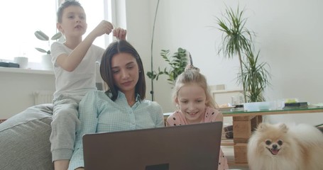 Wall Mural - Happy mom and cute kids using laptop at home