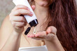 © KatMoy - Brunette caucasian woman using a moisturizing cream for skin in her hands after taking shower.
