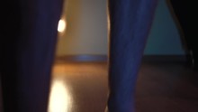 Male Feet Approach The Camera.the Light Behind Is Very Beautiful.In The Room Walking On The Floor Slowly But Surely