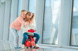 Adorable little girls having fun in airport sitting on suitcase waiting for boarding