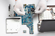 © TATIANA - Details of disassembled laptop and male hands in white gloves, laptop repair concept