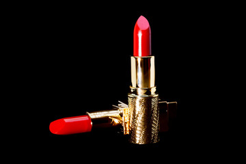 Red lipstick in gold slipcover on black background make up and cosmetic concept