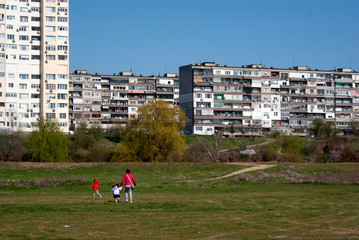 A mother and two children are walking near the city