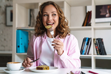 Canvas Print - Photo of joyful beautiful woman eating cake and drinking coffee