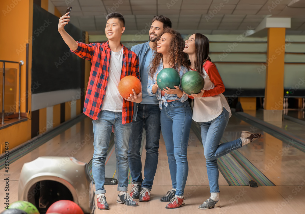 Friends taking selfie while playing bowling in club