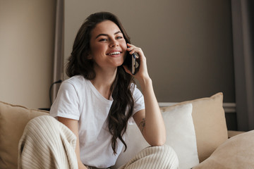 Poster - Beautiful young brunette woman relaxing on a couch at home