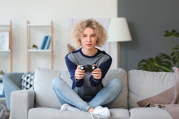 Wall Mural - Beautiful young woman playing video games at home