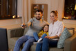 © Syda Productions - family, leisure and people concept - happy smiling father with remote control, mother and little daughter watching tv at home at night