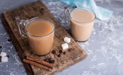 Wall Mural - Cooled coffee with milk, cinnamon sticks, coffee beans, sugar, spoon on the table.