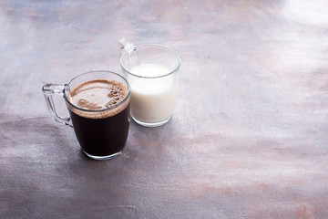 Two glass cups on the table, one in custard coffee, in another fresh milk