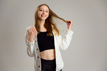 Portrait of a happy caucasian girl with smile in a white jacket on a gray background