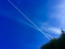 Low Angle View Of Vapor Trails Against Blue Sky On Sunny Day