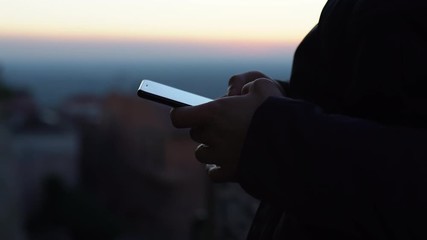 Close-up of man's hands holding modern smartphone, chatting online, reviewing apps and browsing internet outdoors. Male typing messages on mobile phone and sending friends