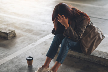 A stressed young asian woman sitting alone in parking lot