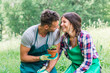 Young loving couple in the park have fun with gardening work during spring day - Millennial are dressed with green aprons