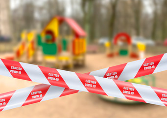 Wall Mural - red and white warning caution tape covid-19 warning over blurred kids playground in the public park