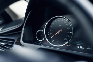 Wall Mural - Close-up of the speedometer on the dashboard of a modern expensive car. The dashboard illumination is reflected. Front background is blurred