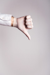 Male hand in a medical glove shows dislike on a white background