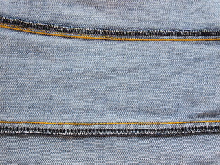 Seam inside old blue jeans The background shows the texture of yellow and black yarn along the seams.