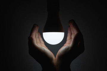 LED bulb with lighting in the human hand with dark background