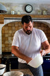 © Victoria_Hunter - A dark haired white man baking bread in his kitchen a navy blue AGA cooker behind him