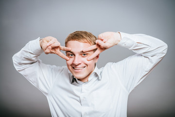 young casual man on eyes showing victory sign while holding a hand in his pocket.