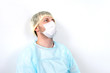 © alenaphoto - Tired doctor in PPE suit sitting and resting near the white wall on the floor, Overworked doctor . Medical mask, cap.