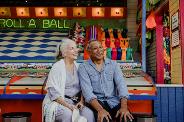 Wall Mural - Smiling senior couple resting by a game booth