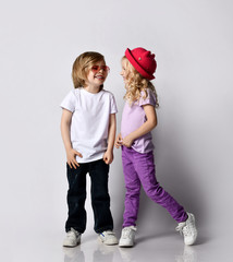 Cheerful laughing kids girl and boy in t-shirts and jeans stand close together, dancing, looking at each other