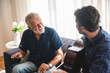 © chokniti - elderly dad and son are playing music at home, relax activity at home with family